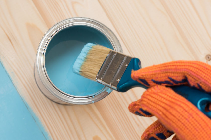 worker paints board. the employee paints the a wooden table. worker paints wooden board. brush in hand.