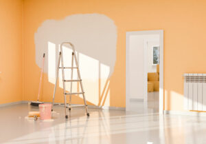 3D rendering of a room with orange walls during a renovation, with a white unpainted patch, a ladder, a bucket of paint and a roller, with sunlight coming through the window.