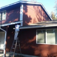 Man painting house brown in Bend OR